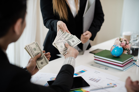 Boss gives a bonus to a female employee who worked well. The company was profitable. The concept of business success.の写真素材