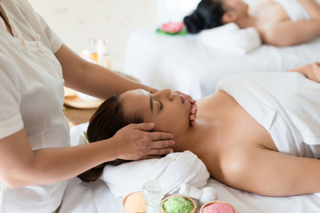 Beautiful Asian girl relaxing receiving facial massage in a spa salonの写真素材