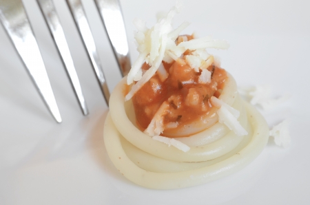Close-up of a Little of Spaghetti Bolognese with a Standing Metal Fork on the Leftの写真素材