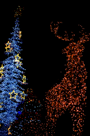 Yellow Deer with Snowman and White Christmas Tree Decoration Lights Vertical Abstract Isolated on Black Backgroundの写真素材