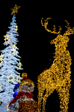 Yellow Deer with Snowman and White Christmas Tree Decoration Lights Vertical Isolated on Black Backgroundの写真素材