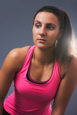 Young Beautiful Sporty Woman Leaning Forward on Gray Backgroundの写真素材