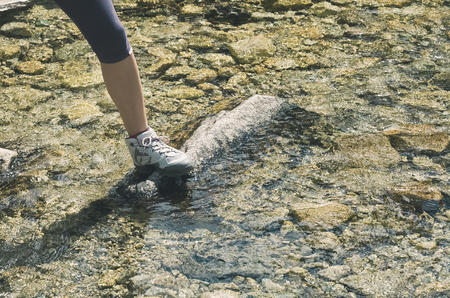 Hiker Crossing Clear Freshwater Brook on Rocksの写真素材