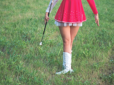 Teen Majorette Girl Outdoors Standing in Grass with Baton Closeupの写真素材