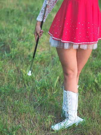 Teen Majorette Girl Outdoors Standing in Grass with Baton Closeupの写真素材