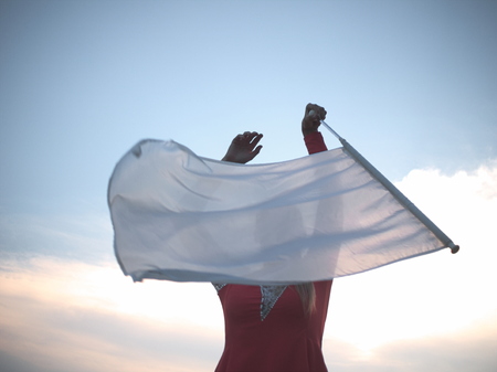 Blonde Teen Majorette Girl with White Flag Outdoors in Red Dressの写真素材