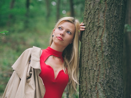 Blonde Woman with Red Dress in Oak Forest on a Summer Dayの写真素材