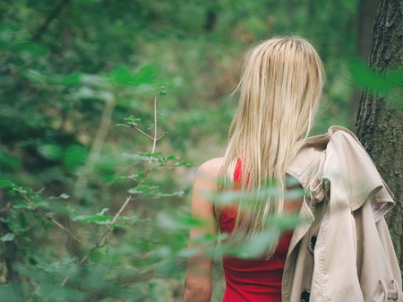 Blonde Woman with Red Dress in Oak Forest on a Summer Day Back Viewの写真素材