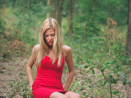 Blonde Woman with Red Dress in Oak Forest on a Summer Dayの写真素材