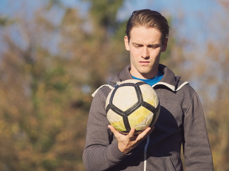 Soccer Player Posing with Football in the Park on a Sunny Autumn Dayの写真素材