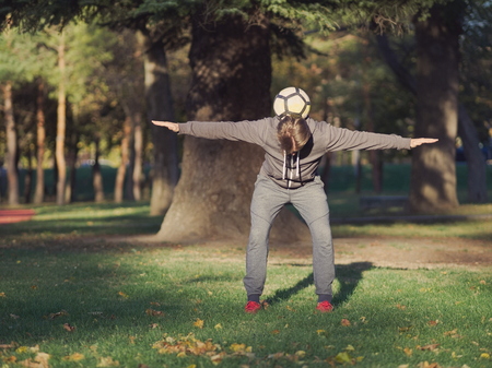 Soccer Player Balancing Football in the Park on a Sunny Autumn Dayの写真素材