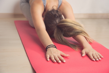 Teen Girl Stretching Arms on Red Yoga Mat Closeupの写真素材