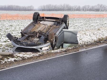 Overturned Car Beside the Wet Road on a Winter Dayの写真素材