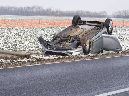Overturned Car Beside the Wet Road on a Winter Dayの写真素材