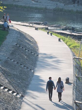 People Walking on Riverside Promenade at RÃ¡ba River on a Sunny Autumn Day in GyÅr, Hungaryの写真素材