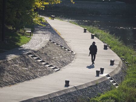 Woman on Riverside Promenade at RÃ¡ba River on a Sunny Autumn Day in GyÅr, Hungaryの写真素材