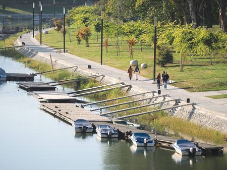 People Walking on Riverside Promenade at Mosoni Danube River on a Sunny Autumn Day in GyÅ‘r,...