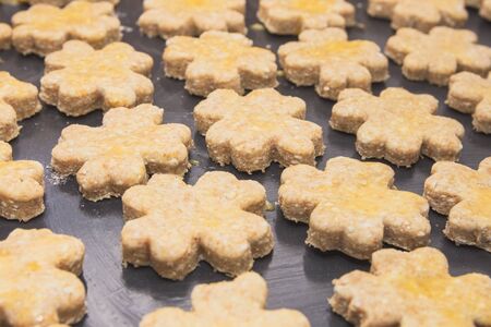 Four-leaf Clover Shaped Raw Cottage Cheese Cookies on Black Baking Sheetの写真素材