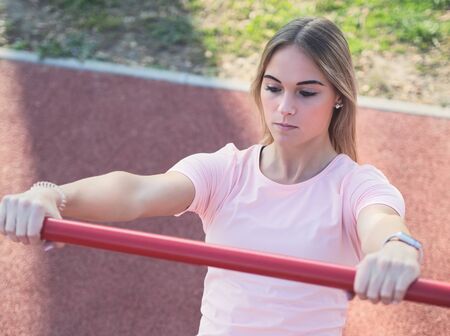 Young Woman Doing Australian Pull Ups in the Park Closeupの写真素材