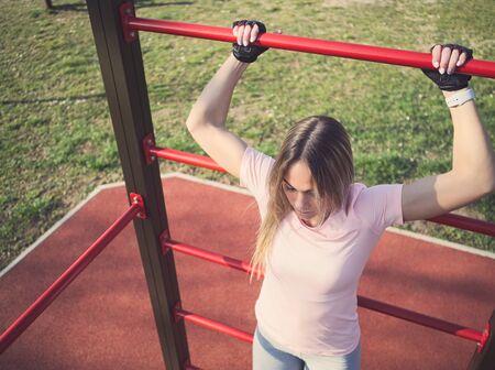 Young Athletic Woman Exercising on Wall Bars in the Park