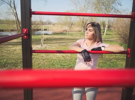 Young Athletic Woman in Sportswear Posing at Wall Bars in the Parkの写真素材