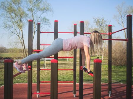 Young Athletic Woman Doing Push Ups on Monkey Bars in the Parkの写真素材