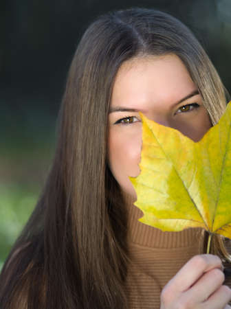 Portrait of a Young Beautiful Long Haired Brunette Woman with Maple Leafの写真素材