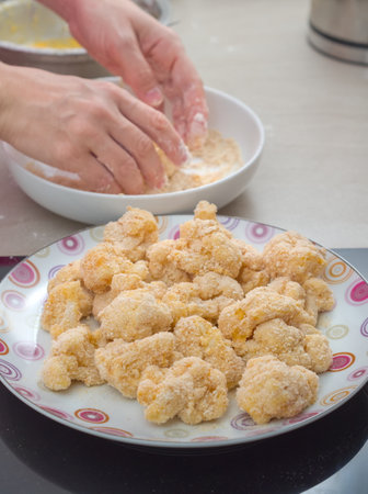Hands Coating Cauliflower in Breadcrumbs in the Kitchen