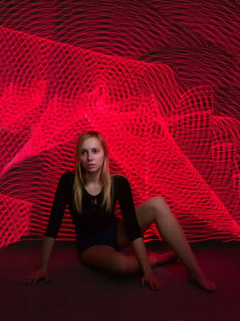 Long Haired Young Blonde Caucasian Woman Long Exposure Red Light Paintingの写真素材