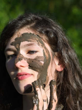 Muddy Face of a Young Long Haired Brunette Caucasian Woman Outdoors on a Sunny Summer Dayの写真素材