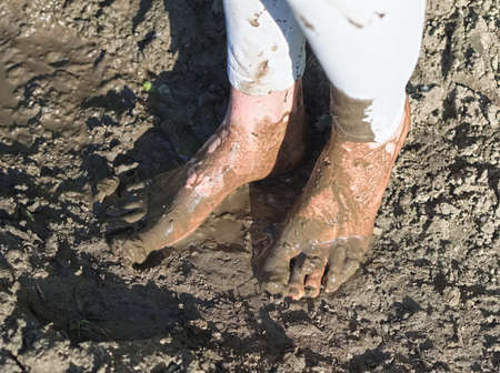 Dirty Wet Muddy Feet of a Young Woman Outdoors on a Sunny Summer Dayの写真素材