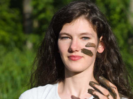 Muddy Face of a Young Long Haired Brunette Caucasian Woman Outdoors on a Sunny Summer Dayの写真素材