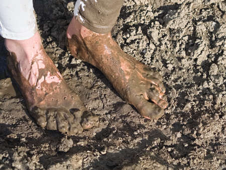 Dirty Wet Muddy Feet of a Young Woman Outdoors on a Sunny Summer Dayの写真素材