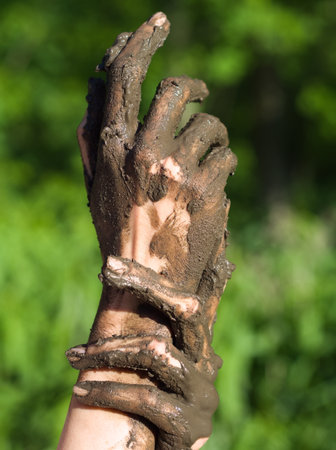 Dirty Wet Muddy Hands of a Young Woman Outdoors on a Sunny Summer Dayの写真素材
