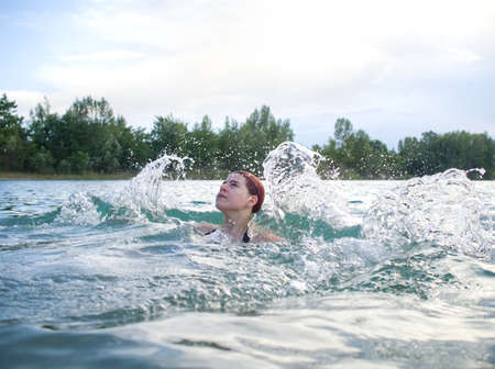 Young Woman with Red Hair Splashing Waterの写真素材