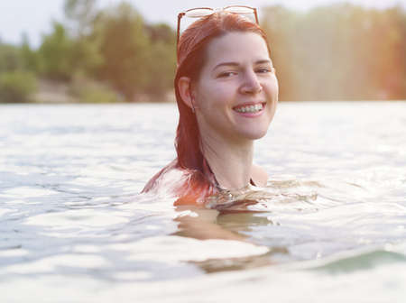 Portrait of a Young Woman with Red Hair Swimming in Lakeの写真素材