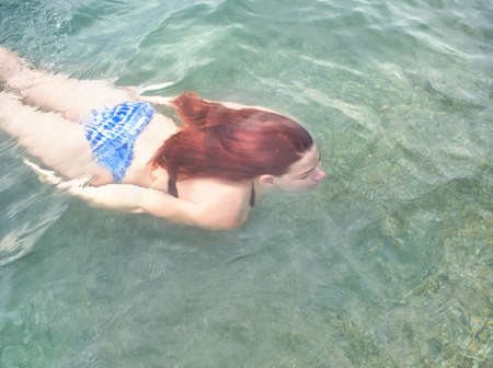 Young Woman with Red Hair Swimming Underwaterの写真素材