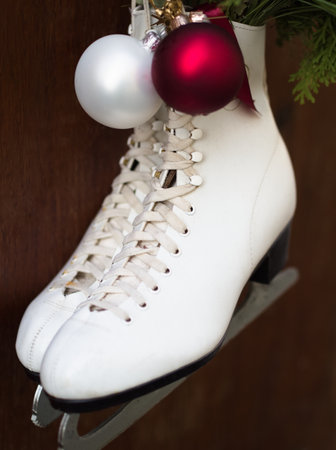 White Ice Skates Hanging on Wood Fence with Christmas Decorationの写真素材