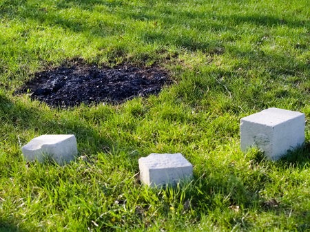 Abandoned outdoor camp fireplace on a green lawn with cement blocks and ashesの写真素材