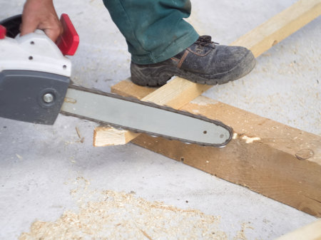 Carpenter cutting wood with a chainsaw on a construction siteの写真素材