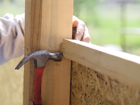 Close-up of a carpenter's hand hammering a nail into a wooden plankの写真素材