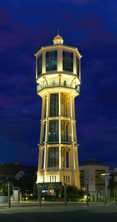 The iconic SiÃ³fok Water Tower stands brilliantly illuminated against a deep blue twilight sky, showcasing its unique octagonal architecture in the heart of SiÃ³fok, Hungary.の写真素材