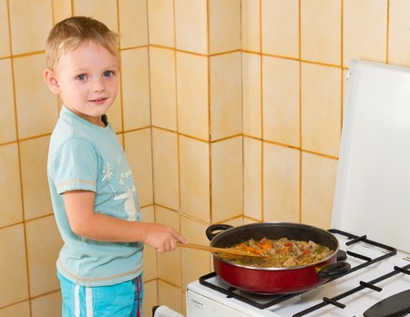 Child prepares meat on the plate. Standing on a stoolの写真素材