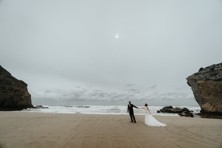 The bride and groom are walking along the beach. Panoramic view. Go holding hand.の写真素材
