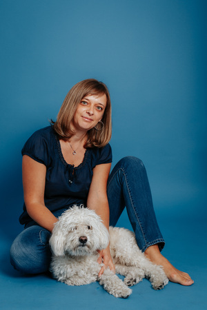 Woman girl sitting on the floor with a white dog. On a blue background.の写真素材