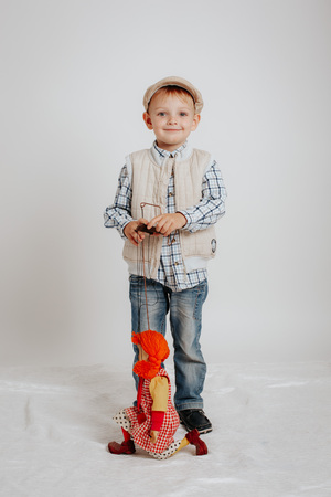 A little boy is standing and playing with a puppet doll.の写真素材