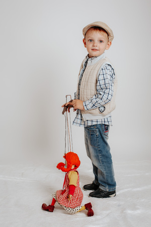A little boy is standing and playing with a puppet doll.の写真素材