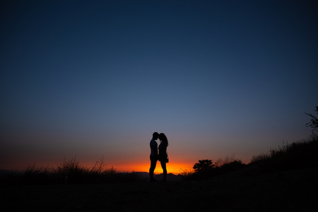 Young couple enjoying sunset in the mountains an amorous couple at sundown.の写真素材