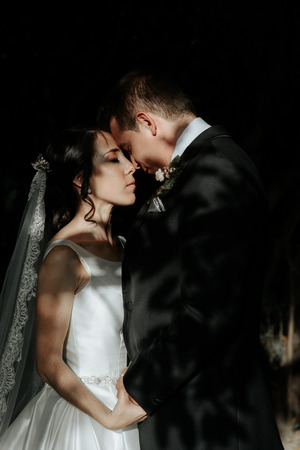 Stylish couple in love. The bride and groom walk on their wedding day in the park, gently hugging. Happy wedding coupleの写真素材