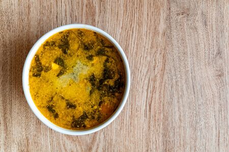 Bowl of soup on a wooden background. Soup of potatoes, spinach, carrots, meat. Copy space.
